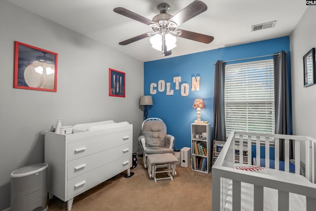 bedroom with light carpet, a crib, and ceiling fan