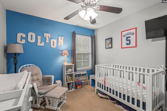 bedroom with a nursery area, carpet floors, and ceiling fan