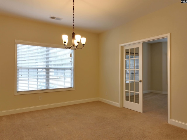 carpeted empty room featuring an inviting chandelier