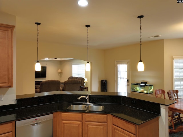 kitchen with dark stone counters, dishwasher, sink, and hanging light fixtures