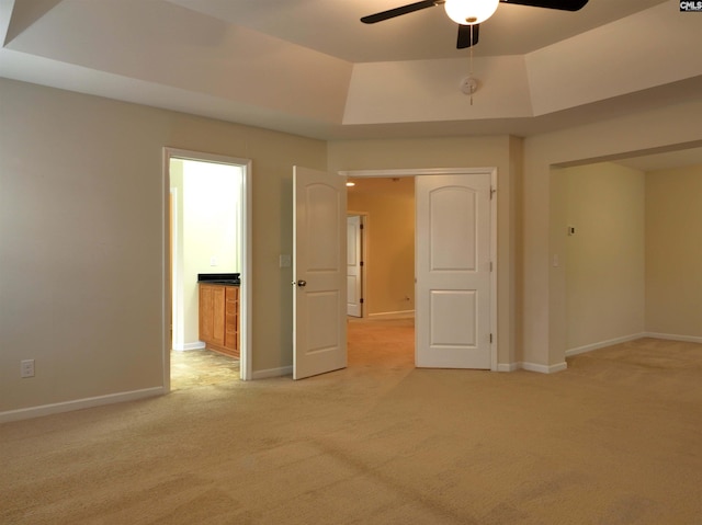 carpeted empty room with a tray ceiling and ceiling fan