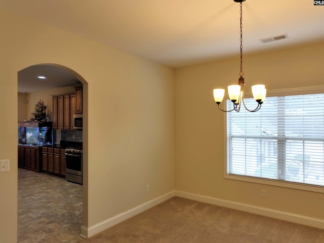 carpeted empty room featuring a notable chandelier