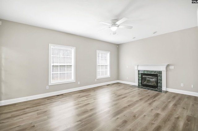 unfurnished living room featuring hardwood / wood-style flooring, ceiling fan, and a tiled fireplace