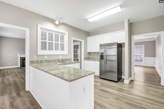 kitchen with stainless steel fridge with ice dispenser, sink, white cabinets, kitchen peninsula, and light hardwood / wood-style flooring