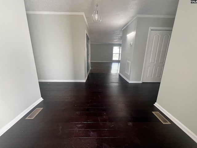 corridor featuring dark wood-type flooring, ornamental molding, and a textured ceiling