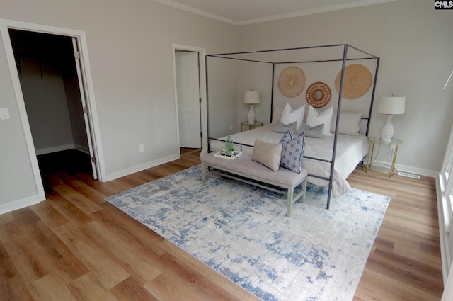 bedroom featuring hardwood / wood-style floors, a spacious closet, and ornamental molding