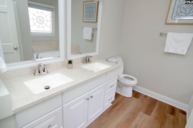 bathroom with wood-type flooring, toilet, vanity, and a tub