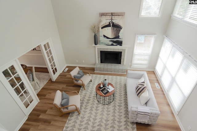 living room with a towering ceiling, hardwood / wood-style floors, a tile fireplace, and a wealth of natural light