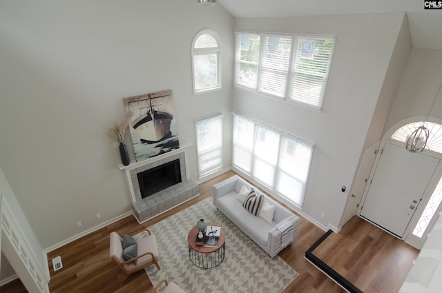 living room featuring a tile fireplace, hardwood / wood-style floors, and high vaulted ceiling