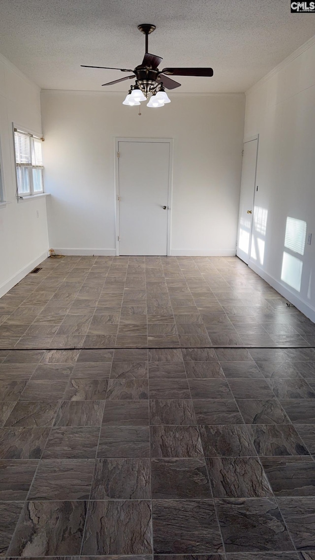 empty room with ceiling fan and a textured ceiling