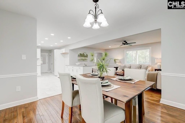 dining space featuring ceiling fan with notable chandelier and light wood-type flooring