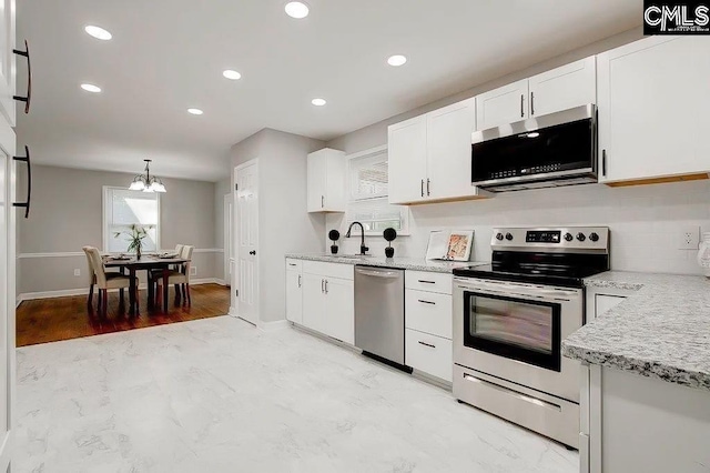 kitchen with white cabinetry, appliances with stainless steel finishes, sink, and pendant lighting