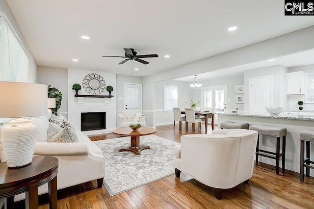 living room with ceiling fan, a large fireplace, and hardwood / wood-style floors