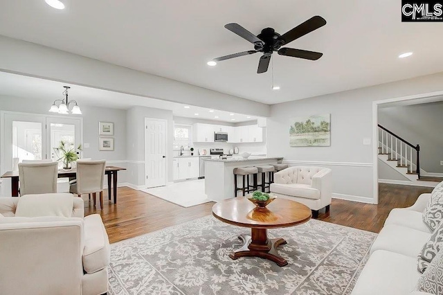 living room featuring sink, ceiling fan with notable chandelier, and light hardwood / wood-style floors