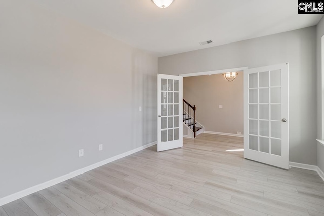 empty room featuring baseboards, french doors, visible vents, and light wood-style floors