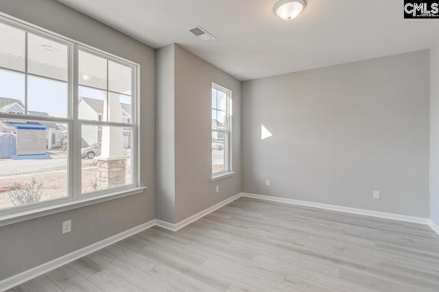 unfurnished room featuring light wood-style flooring, visible vents, and baseboards