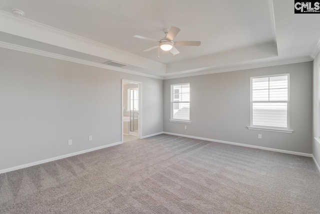 unfurnished room with ornamental molding, a raised ceiling, visible vents, and baseboards