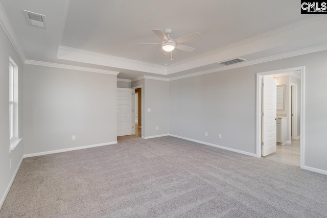 unfurnished room with a raised ceiling, visible vents, light carpet, ceiling fan, and baseboards