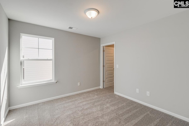 unfurnished room with carpet floors, visible vents, and baseboards