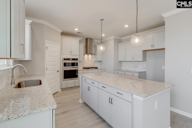 kitchen with a center island, crown molding, double oven, a sink, and wall chimney exhaust hood