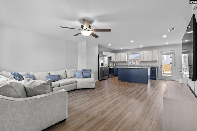 living room with ceiling fan and light hardwood / wood-style floors