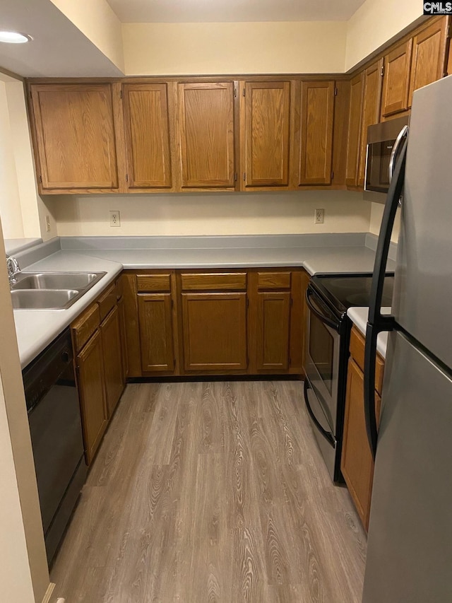 kitchen featuring stainless steel appliances, sink, and light hardwood / wood-style flooring