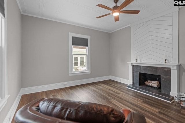 living room featuring hardwood / wood-style flooring, ceiling fan, a fireplace, and crown molding