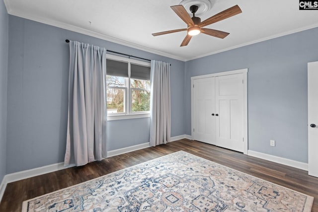 unfurnished bedroom featuring crown molding, ceiling fan, dark hardwood / wood-style flooring, and a closet