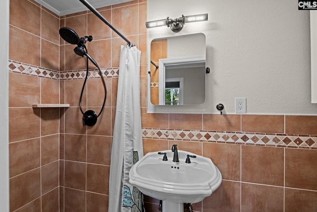 bathroom with sink, curtained shower, and tile walls