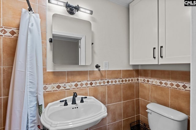 bathroom featuring tile walls, sink, and toilet