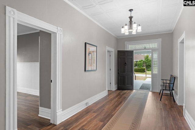 foyer featuring an inviting chandelier, crown molding, and dark hardwood / wood-style floors