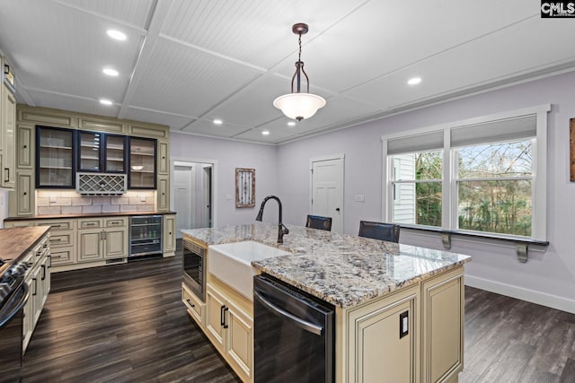 kitchen with dishwasher, wine cooler, hanging light fixtures, a center island with sink, and cream cabinetry