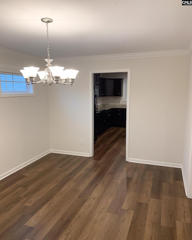 unfurnished dining area featuring dark wood-type flooring, ornamental molding, and a chandelier