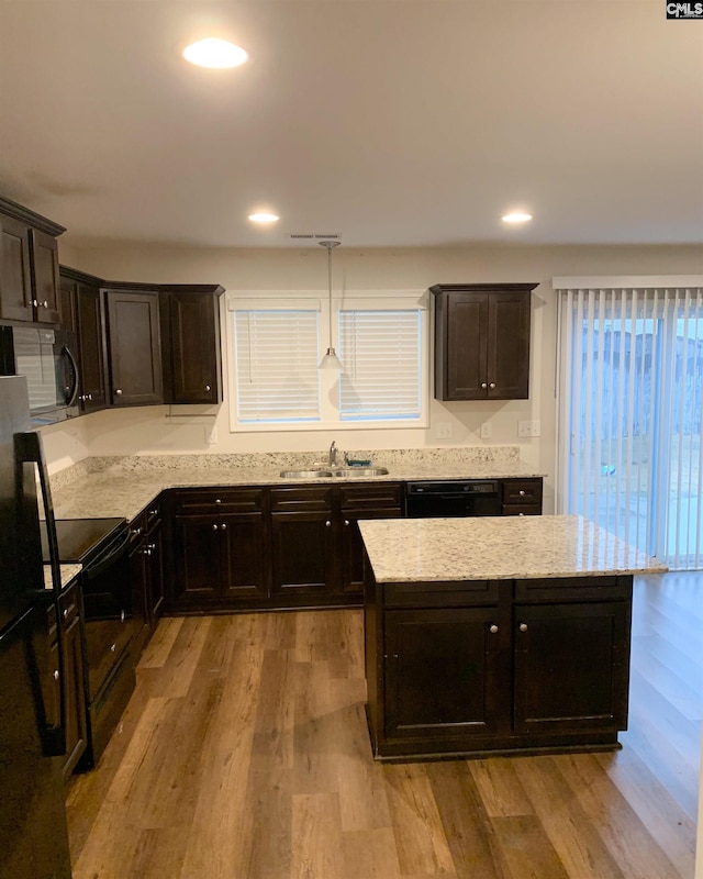 kitchen with pendant lighting, sink, light hardwood / wood-style floors, black appliances, and dark brown cabinets