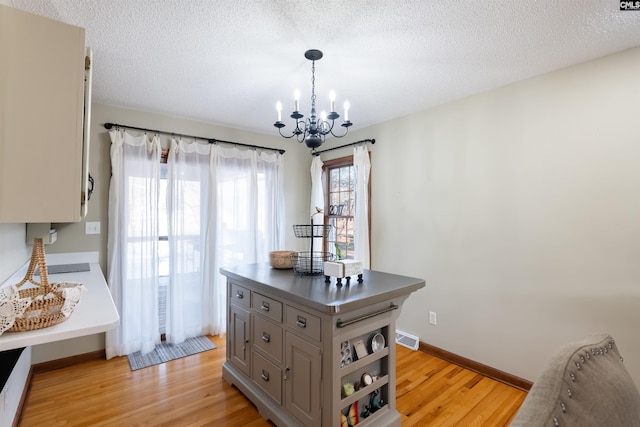 interior space featuring an inviting chandelier, light hardwood / wood-style floors, and a textured ceiling