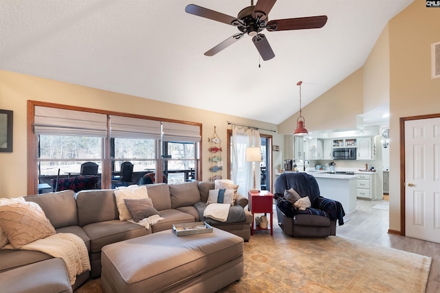 living room with high vaulted ceiling, light hardwood / wood-style floors, sink, and ceiling fan