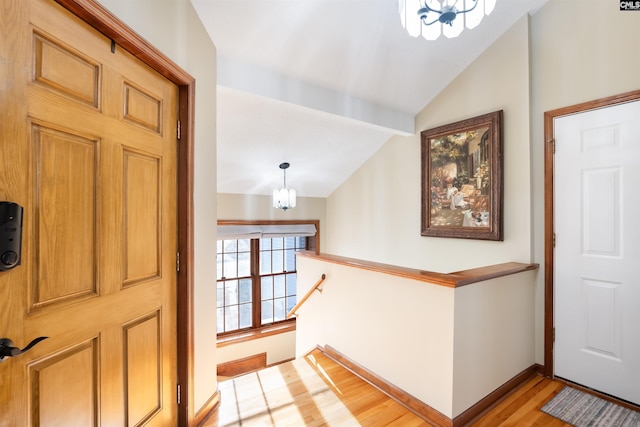 entryway with an inviting chandelier, vaulted ceiling, and light hardwood / wood-style floors