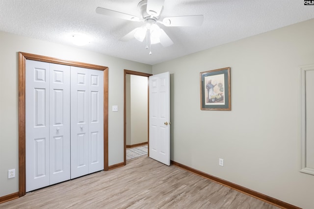 unfurnished bedroom featuring ceiling fan, a textured ceiling, light hardwood / wood-style floors, and a closet