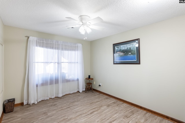 empty room featuring ceiling fan, light hardwood / wood-style floors, and a textured ceiling