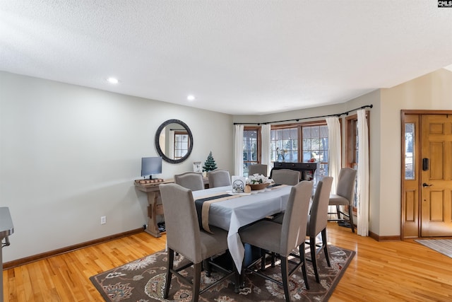 dining space with wood-type flooring and a textured ceiling