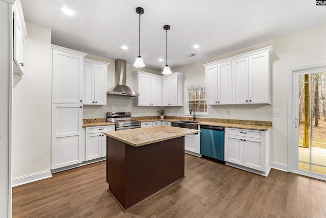 kitchen featuring white cabinetry, stainless steel appliances, a center island, and wall chimney range hood