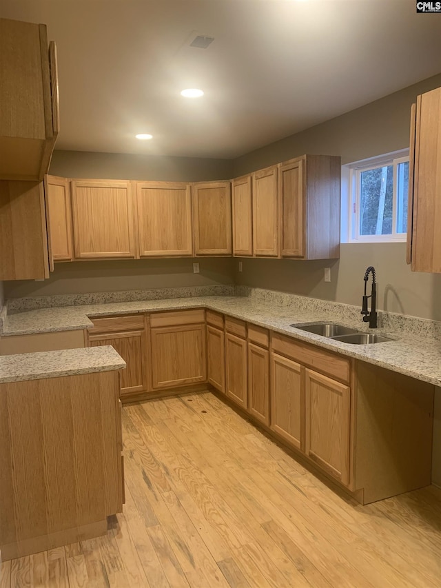 kitchen featuring light stone countertops, sink, and light wood-type flooring