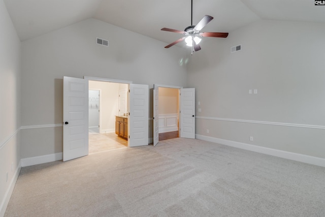 unfurnished bedroom with ceiling fan, connected bathroom, high vaulted ceiling, and light carpet