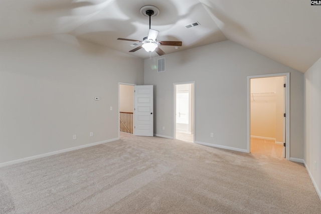 unfurnished bedroom with connected bathroom, lofted ceiling, a walk in closet, light colored carpet, and ceiling fan