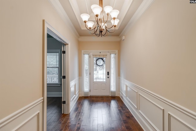 entrance foyer featuring an inviting chandelier, crown molding, and dark hardwood / wood-style floors