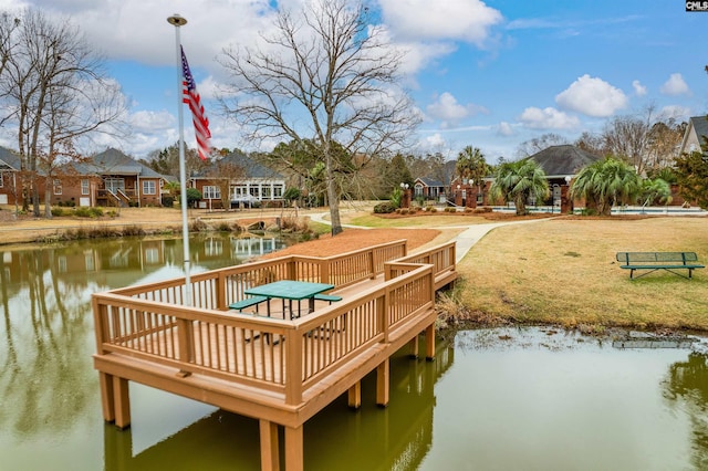 view of dock with a lawn and a water view