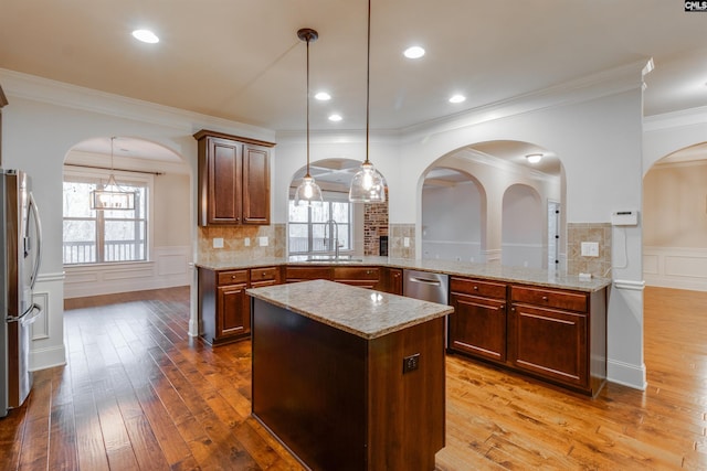 kitchen with sink, light hardwood / wood-style flooring, hanging light fixtures, stainless steel appliances, and kitchen peninsula