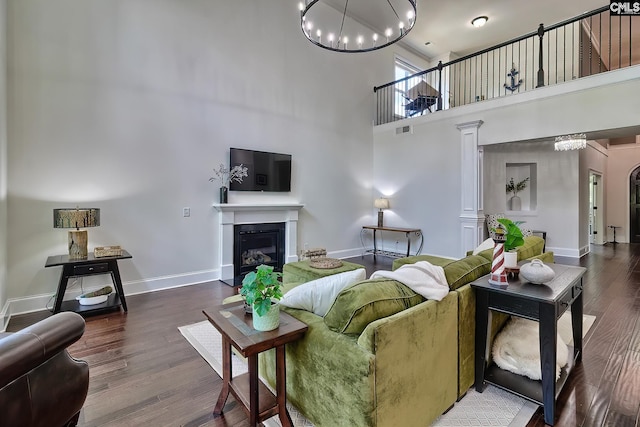 living room with an inviting chandelier, a towering ceiling, and hardwood / wood-style floors