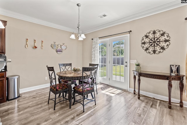 dining room with ornamental molding, an inviting chandelier, and light hardwood / wood-style flooring