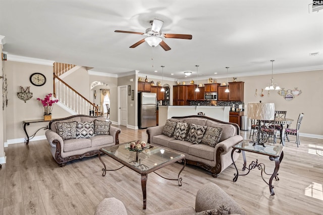 living room featuring crown molding, ceiling fan with notable chandelier, and light hardwood / wood-style floors